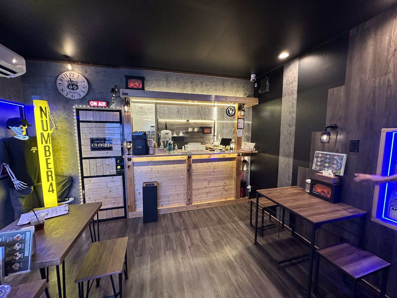 木のカウンターとテーブル席、青い照明があるnumber4の店内全景