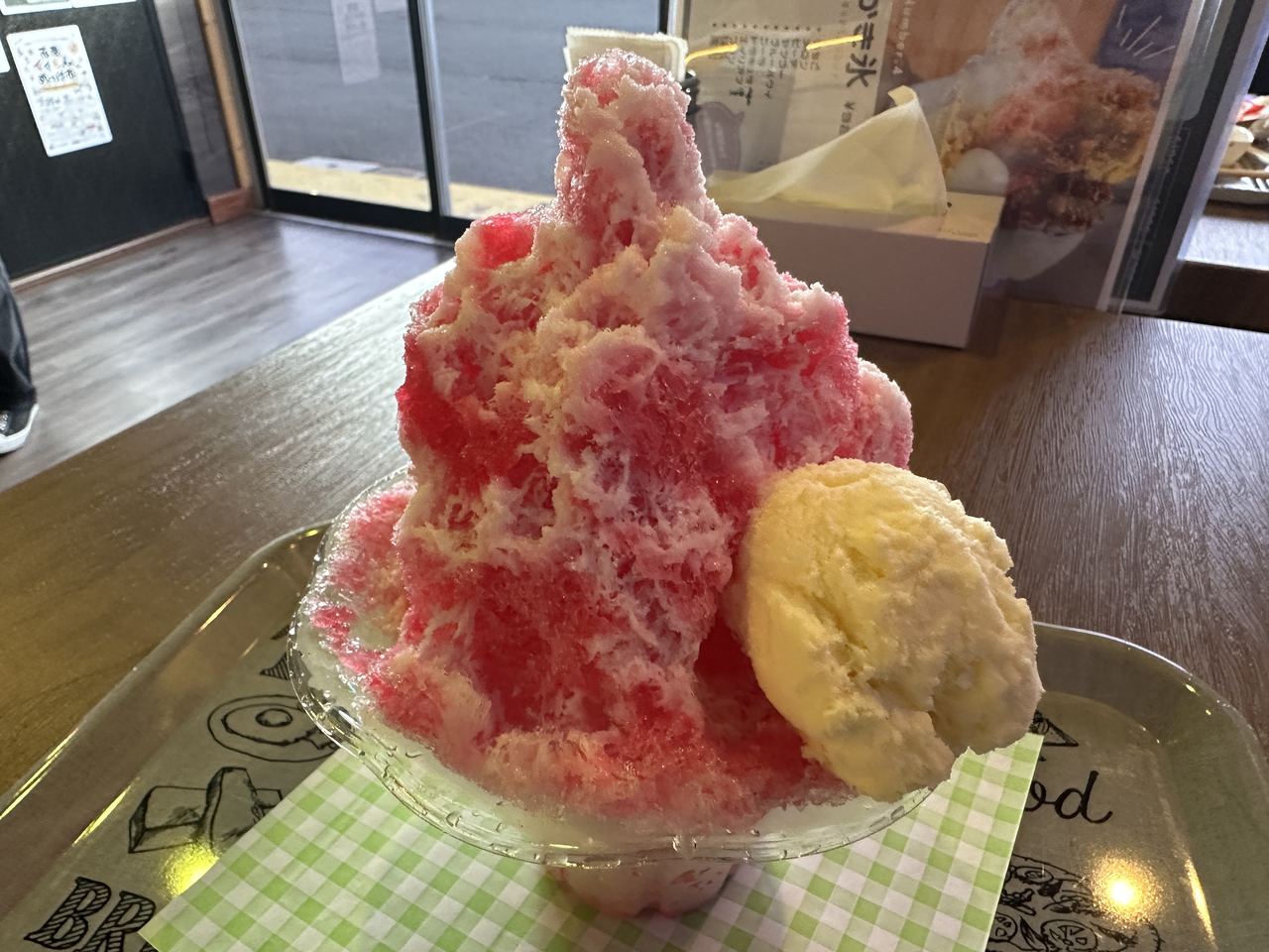 赤いシロップがかかった山盛りのかき氷と、添えられた丸いアイス